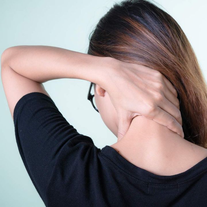 A woman holding the back of her neck in discomfort